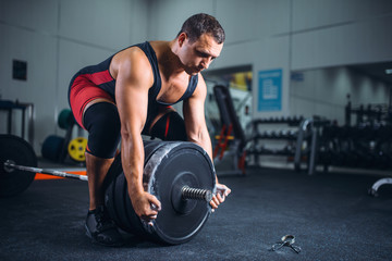 Fototapeta na wymiar Male powerlifter prepares a barbell in gym