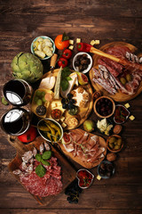 Italian antipasti wine snacks set. Cheese variety, Mediterranean olives, crudo, Prosciutto di Parma, salami and wine in glasses over grunge background.