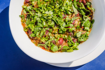 Lobio dish with red beans, spices and herbs. On blue table.