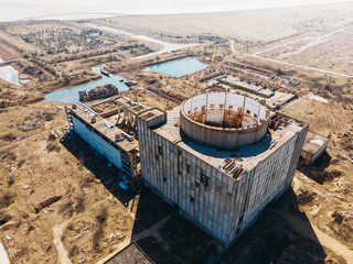 Aerial top view of abandoned and ruined Nuclear Power Plant in Shelkino, Crimea. Large USSR industrial construction with round tower of atomic reactor