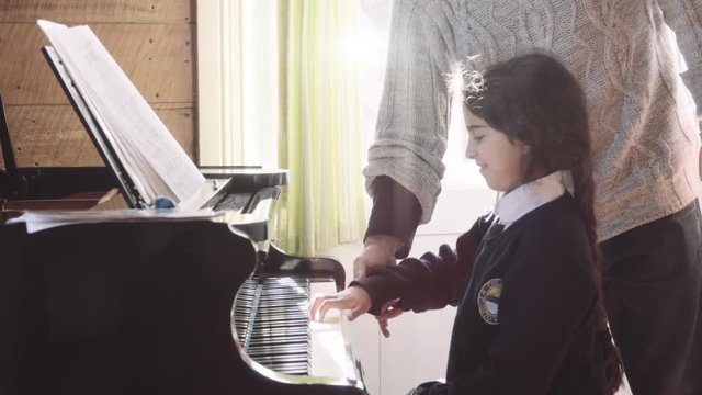 Hispanic man teaching piano to a little girl in a classroom. 4k	