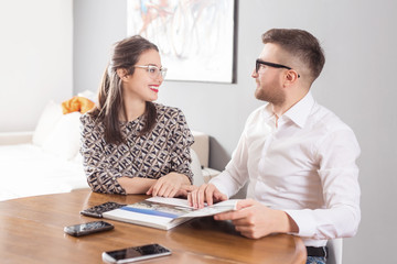 Obraz premium Young business married couple sitting at table and reading a book