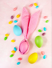 Napkin Easter Bunny, decoration eggs and Easter candy on pink background.