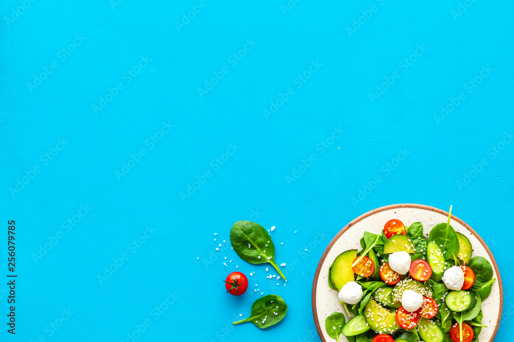 Wall mural Healthy lunch. Fresh vegetable salad on blue background top view copy space