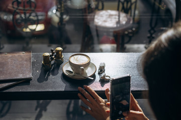 Attractive smiling girl taking photo cup of latte, using smartphone