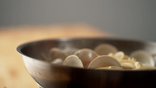 Camera follows cooking pasta with clams in a pan. Shot with high speed camera, phantom flex 4K. Slow Motion.
