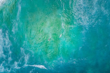 Two surfers rowing in opposite directions - aerial view with copy space