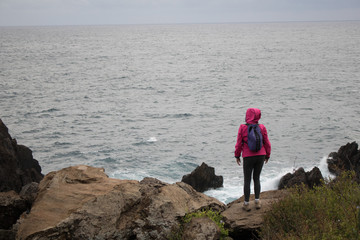 Woman looking out to the sea on a rocky shore