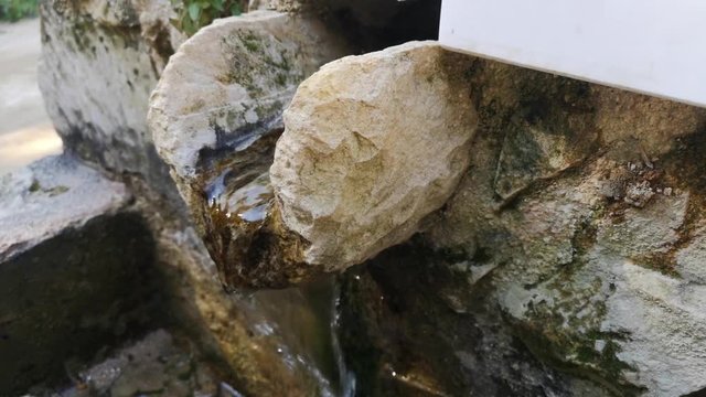 Close-up of a person washing their hands under a natural spout at Kritou Terra waterfalls in Cyprus