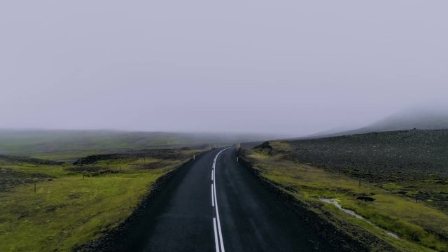 Aerial drone footage following incredible breathtaking winding mountain road covered by cloud, mist or fog. Creepy and spooky atmosphere. Exciting unexplored travel destination