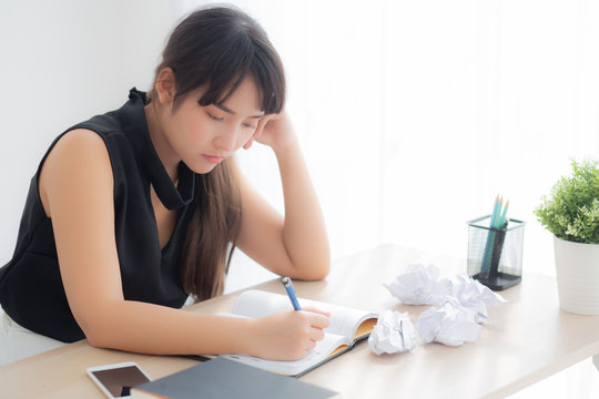 Beautiful asian woman tired and stressed with writing overworked at desk, girl with worried not idea with notebook and crumpled paper at office, freelance and business concept.