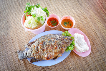 Set of grilled tilapia fish with salt and fresh vegetable chili sauce in asian thai  style food on plate