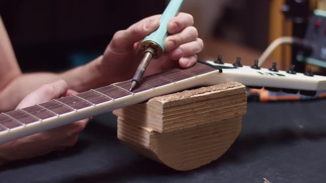 Guitarist changes the fret of the guitar neck