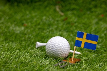 Golf ball with flag of Sweden on green grass