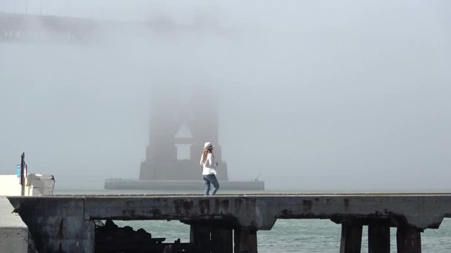 Woman taking Pictures at Foggy Golden Gate Bridge