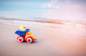 Yellow duck toy and colorful car on sand in the beach