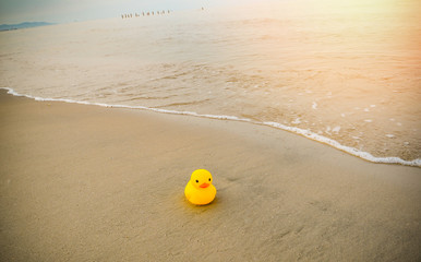 Yellow duck toy on sand in the beach