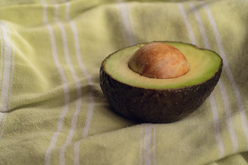 A sliced fresh avocado rests on a green tea towel