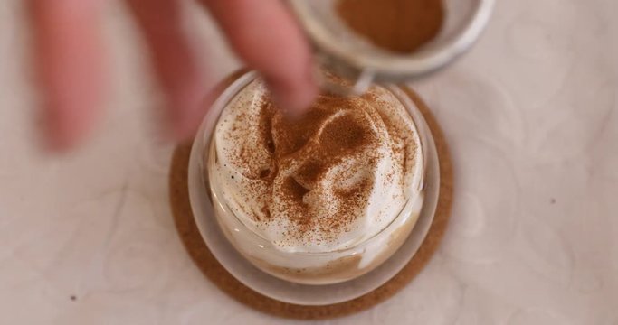 Sprinkling with cinnamon powder on espresso con panna with whipping cream