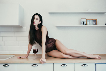 Woman in underwear with glass of wine sitting on table, shallow depth of field