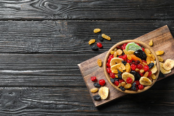 Bowl of different dried fruits on wooden background, top view with space for text. Healthy lifestyle