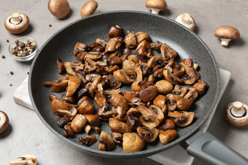 Frying pan with mushrooms on grey table