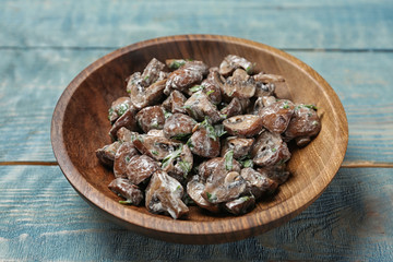 Bowl of fried mushrooms with sauce on wooden table
