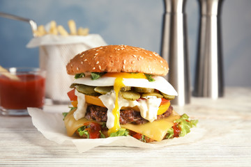 Tasty burger with fried egg on table against blurred background