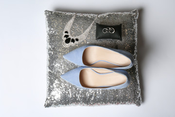 Pillow with lady's shoes and jewelry on light background, top view