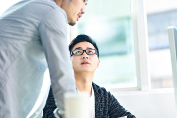 two asian corporate executives discussing business in office