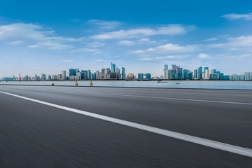 Fototapeta premium Foreground highway asphalt pavement city building commercial building office building