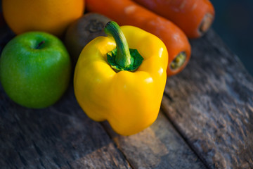 Still life fruit with yellow bell pepper green apple carrot orange and kiwi on rustic wood background