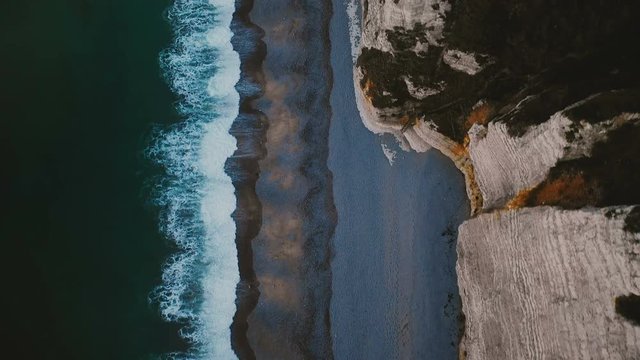 Top view, drone flying directly above famous white cliffs at Normandy sea shore, calm azure waves and alabaster rocks.