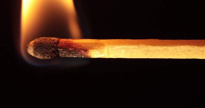 A match ignites and burns quickly as the blackened stick curls out of the frame.