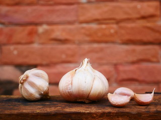 garlic on wooden table and brick wall background