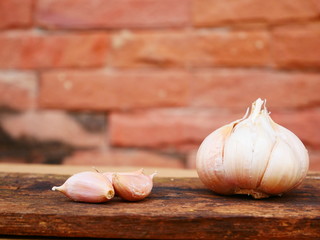 garlic on wooden table and brick wall background