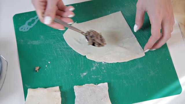 Girl in an apron preparing envelopes with mushrooms for baking at home.