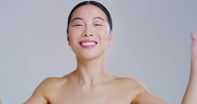 Slow motion of asian woman with beautiful face and perfect skin just cleaned from impurities pampering it gently with fingers.
