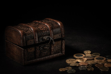 old wooden chest with coins on a black background
