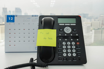 sticky note with call me back message on IP landline phone with December calendar backdrop