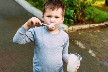 child eats with a spoon oxygen cocktail outdoors