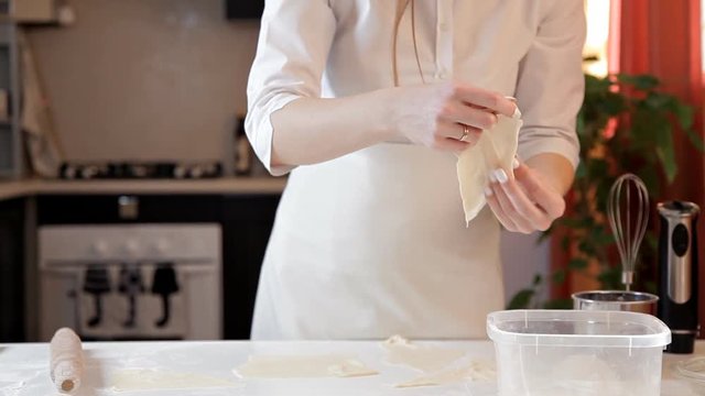 The girl in the apron puts the remains of raw dough in a plastic container