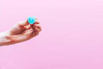 Close up of woman hand folding menstrual cup showing how to use, c form. Women health concept, zero waste alternatives