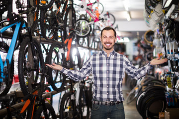 Fototapeta na wymiar interested man in bicycle shop chooses for himself sports bike