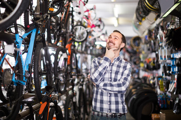 Fototapeta na wymiar Man 29-35 years old is choosing in sports store convenient bike