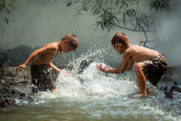 Asia children on river / The boy friend happy funny playing water in the water stream