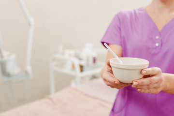 Closeup of female beautician holding plate with ingredients for removal mask