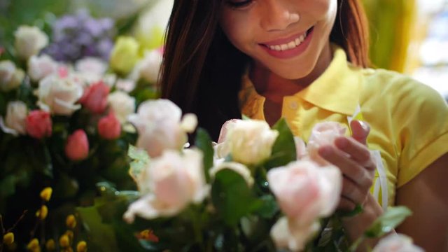 Close up of young woman touching bunch of roses and smiling