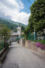 narrow street of an Italian quiet village in the Alps leading to the city church. measured life in the commune. traditional european cityscape.