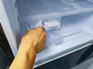 Man hand twisting for ice from the ice maker in new refrigerator.